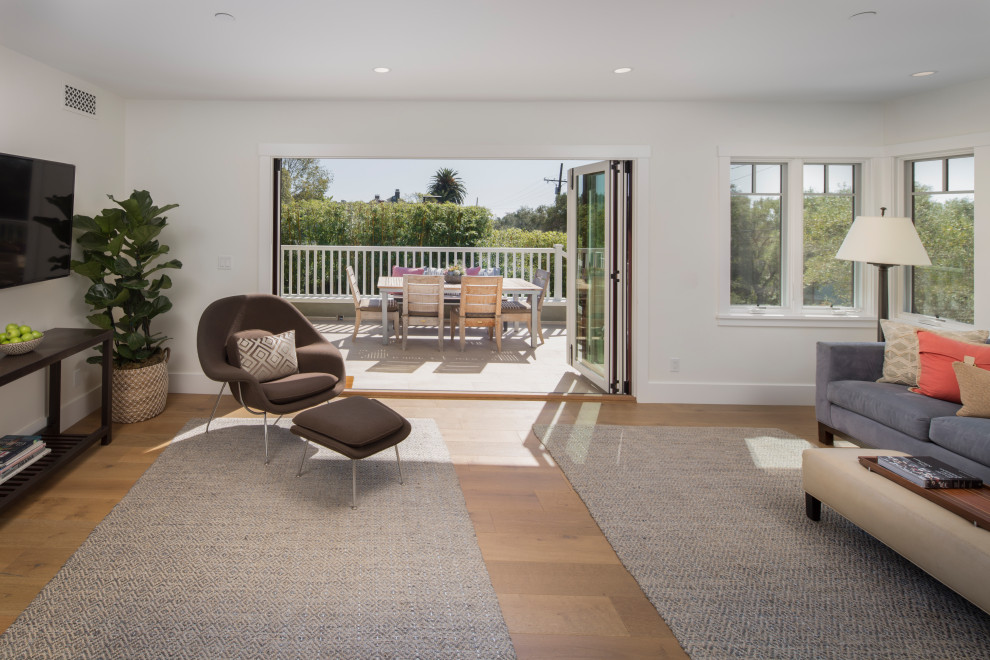 Foto di un soggiorno stile americano aperto con pareti bianche, pavimento in legno massello medio, TV a parete e pavimento marrone