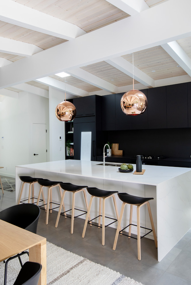 Large midcentury single-wall open plan kitchen in Vancouver with flat-panel cabinets, black cabinets, quartz benchtops, black splashback, with island, grey floor, an undermount sink, panelled appliances, concrete floors and black benchtop.
