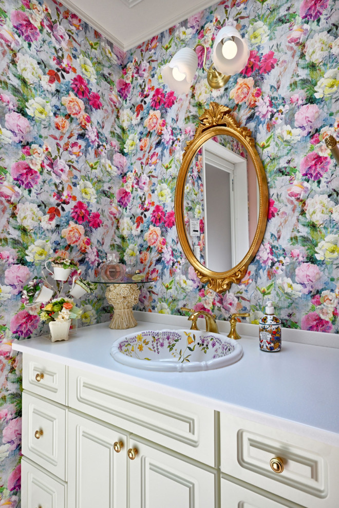 Small classic cloakroom in Other with raised-panel cabinets, white cabinets, pink walls, vinyl flooring, a built-in sink, solid surface worktops, pink floors, white worktops, a feature wall, a built in vanity unit, a wallpapered ceiling and wallpapered walls.