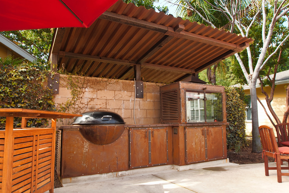 Photo of a mid-sized industrial backyard patio in Santa Barbara with an outdoor kitchen, concrete slab and an awning.