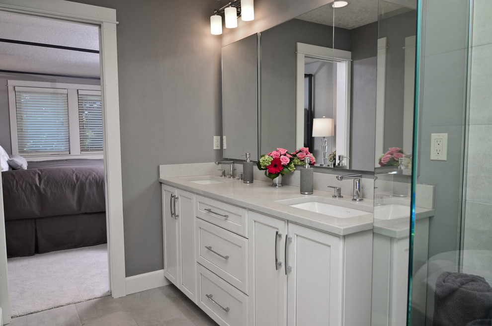 This is an example of a mid-sized traditional master bathroom in Portland with recessed-panel cabinets, white cabinets, a freestanding tub, an alcove shower, gray tile, ceramic tile, grey walls, ceramic floors, an undermount sink and solid surface benchtops.