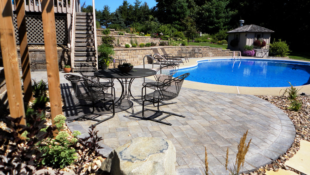This is an example of a large transitional backyard round pool in Cedar Rapids with brick pavers.