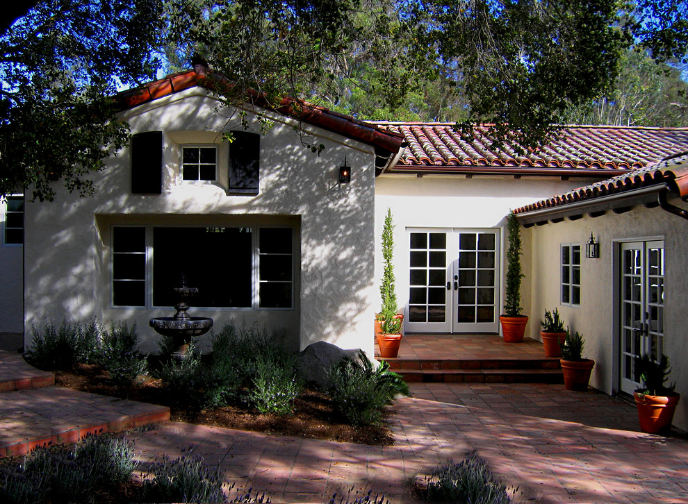 Photo of a mid-sized mediterranean one-storey stucco white house exterior in Santa Barbara with a clipped gable roof and a tile roof.