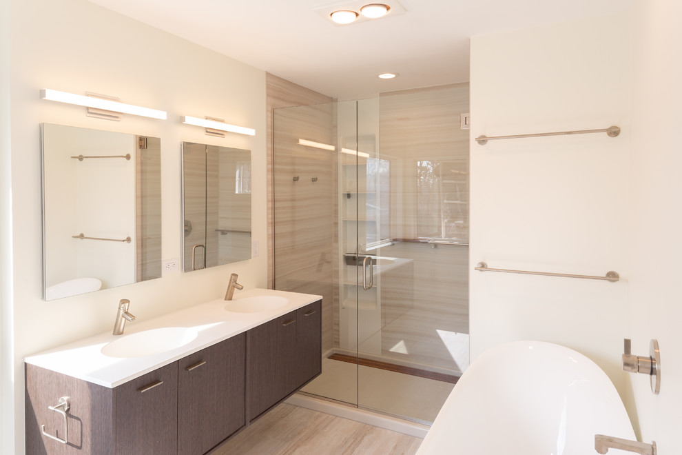 Photo of a mid-sized modern master bathroom in Detroit with flat-panel cabinets, brown cabinets, a freestanding tub, an alcove shower, white walls, laminate floors, an integrated sink, engineered quartz benchtops, multi-coloured floor, a hinged shower door, white benchtops, a two-piece toilet, beige tile and porcelain tile.