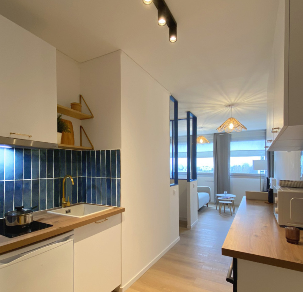 Inspiration for a mid-sized modern galley open plan kitchen in Lille with a single-bowl sink, beaded inset cabinets, white cabinets, laminate benchtops, blue splashback, ceramic splashback, white appliances, laminate floors, no island, beige floor and beige benchtop.