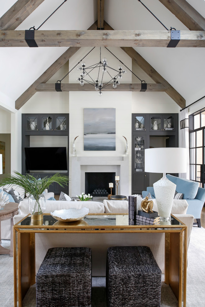 This is an example of a beach style open concept family room in Nashville with white walls, medium hardwood floors, a standard fireplace, a wall-mounted tv and brown floor.