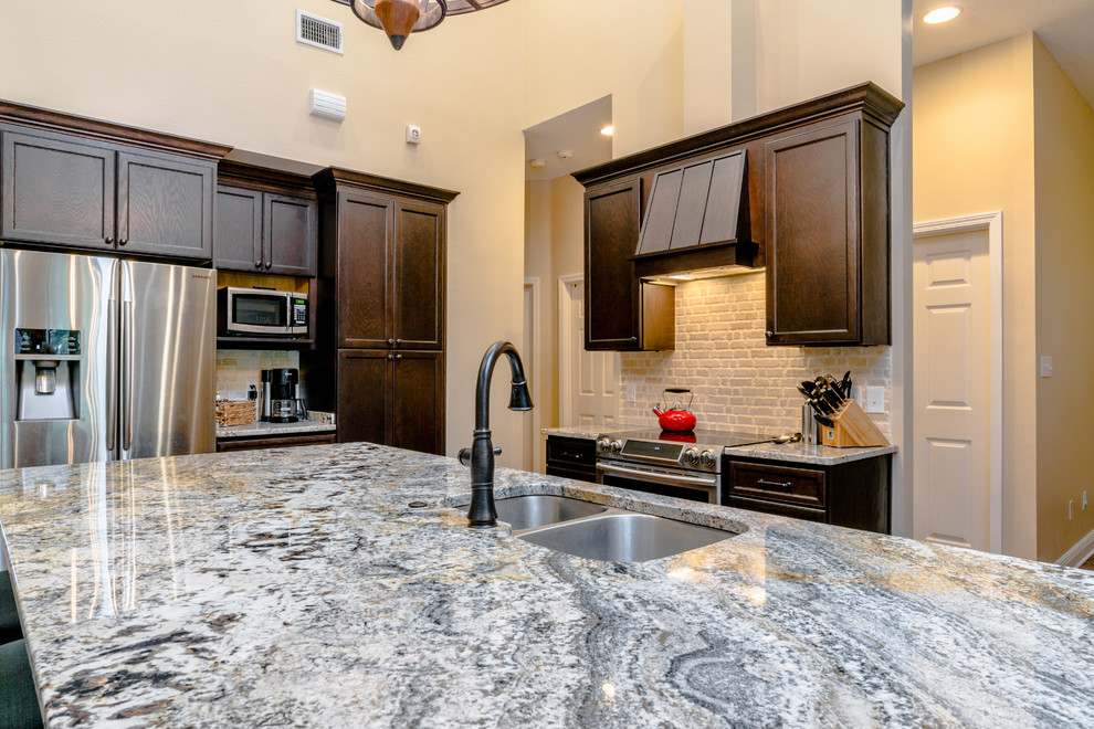 Large transitional l-shaped vinyl floor eat-in kitchen photo in Miami with an undermount sink, shaker cabinets, dark wood cabinets, granite countertops, beige backsplash, porcelain backsplash, stainless steel appliances and an island