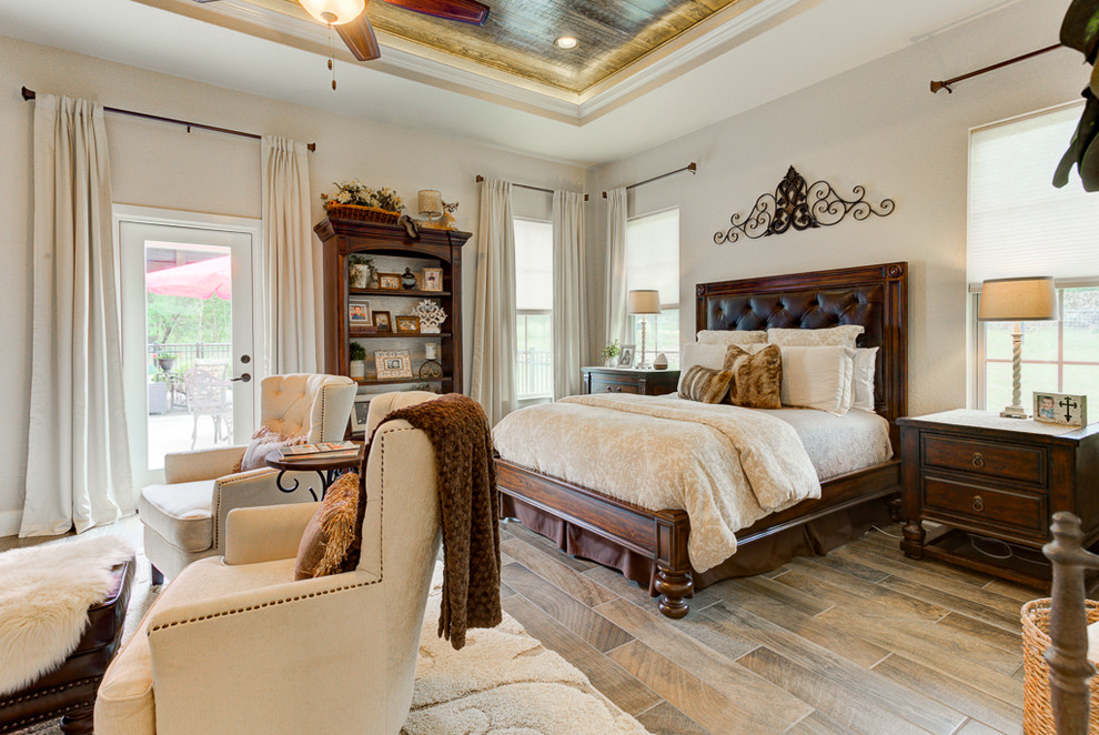 Inspiration for a mid-sized country master bedroom in Austin with beige walls, porcelain floors, a standard fireplace, a stone fireplace surround and brown floor.