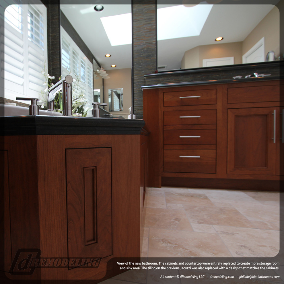 This is an example of a large contemporary master bathroom in Philadelphia with an undermount sink, shaker cabinets, medium wood cabinets, granite benchtops, beige tile, a drop-in tub, an alcove shower, a two-piece toilet, mosaic tile, beige walls and limestone floors.