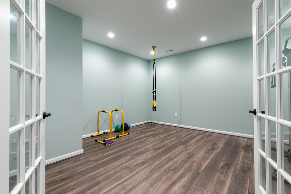 Photo of a mid-sized transitional home weight room in DC Metro with blue walls, vinyl floors and brown floor.