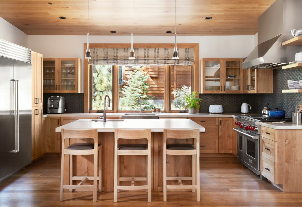 This is an example of a country u-shaped kitchen in Sacramento with a farmhouse sink, shaker cabinets, medium wood cabinets, grey splashback, stainless steel appliances, medium hardwood floors, with island and brown floor.