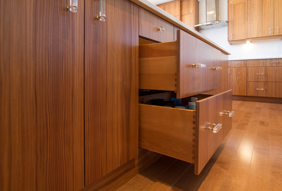Inspiration for a large modern l-shaped medium tone wood floor eat-in kitchen remodel with an undermount sink, flat-panel cabinets, medium tone wood cabinets, quartz countertops, white backsplash, ceramic backsplash, stainless steel appliances and an island