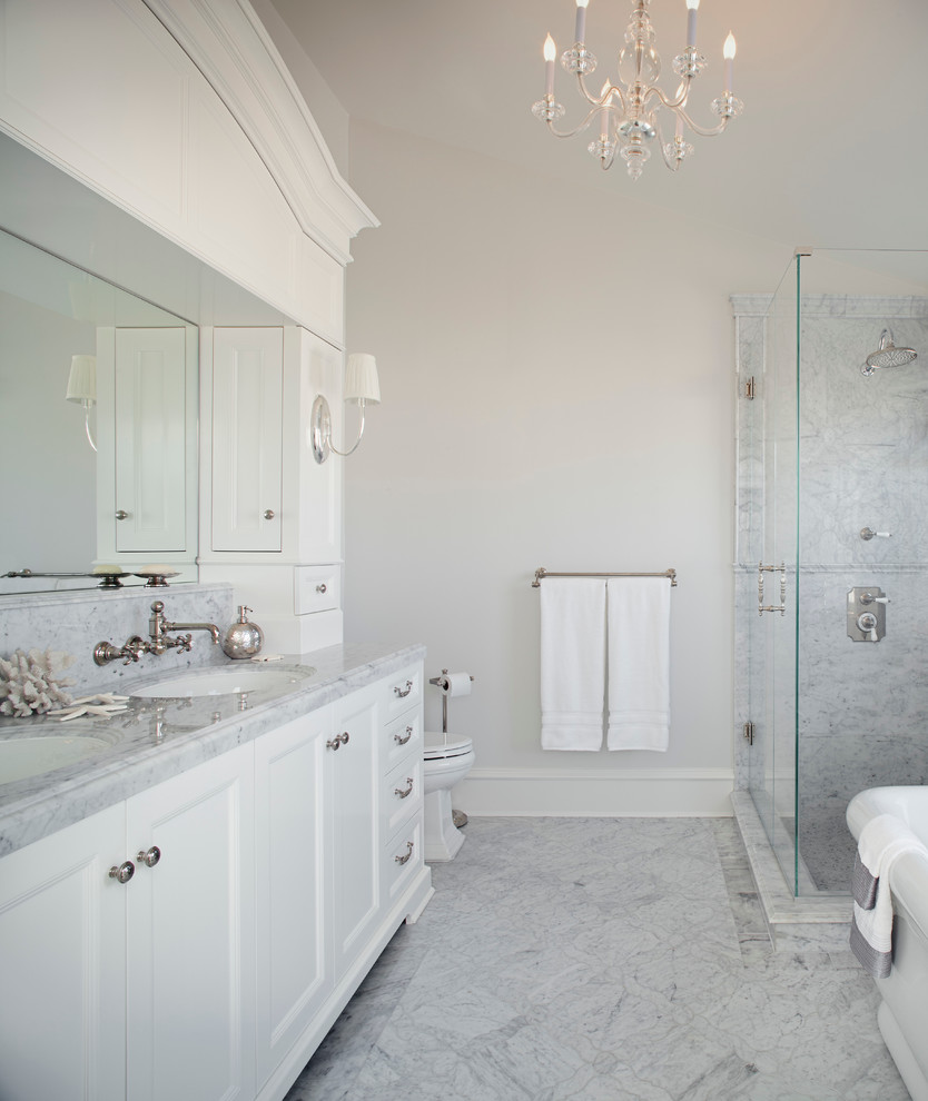 Design ideas for a mid-sized traditional master bathroom in Los Angeles with an undermount sink, recessed-panel cabinets, white cabinets, marble benchtops, a freestanding tub, a one-piece toilet, gray tile, stone tile, a corner shower, white walls and porcelain floors.