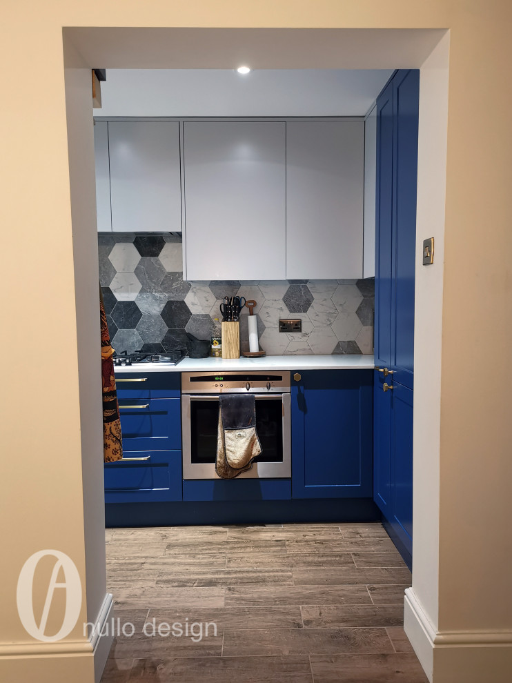 Photo of a small contemporary l-shaped separate kitchen in London with a drop-in sink, shaker cabinets, blue cabinets, quartzite benchtops, grey splashback, cement tile splashback, stainless steel appliances, ceramic floors, no island, brown floor, white benchtop and recessed.