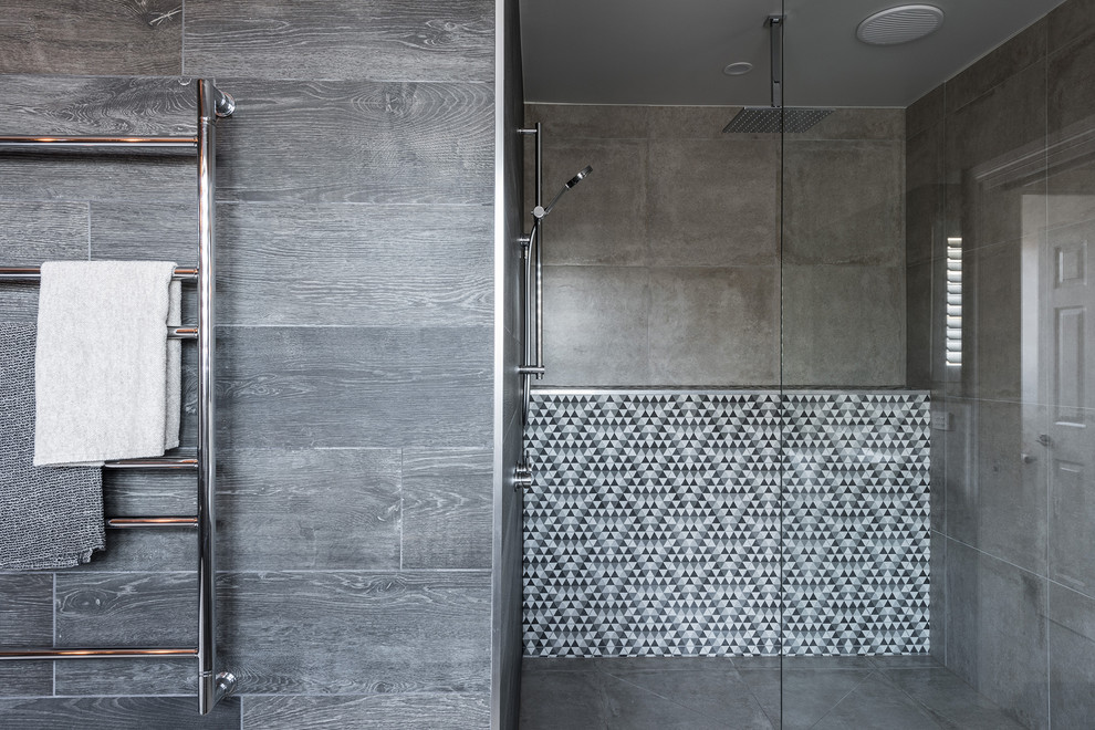 Photo of a mid-sized contemporary master bathroom in Melbourne with flat-panel cabinets, grey cabinets, a freestanding tub, an open shower, gray tile, ceramic tile, grey walls, ceramic floors, a vessel sink, engineered quartz benchtops, grey floor and an open shower.
