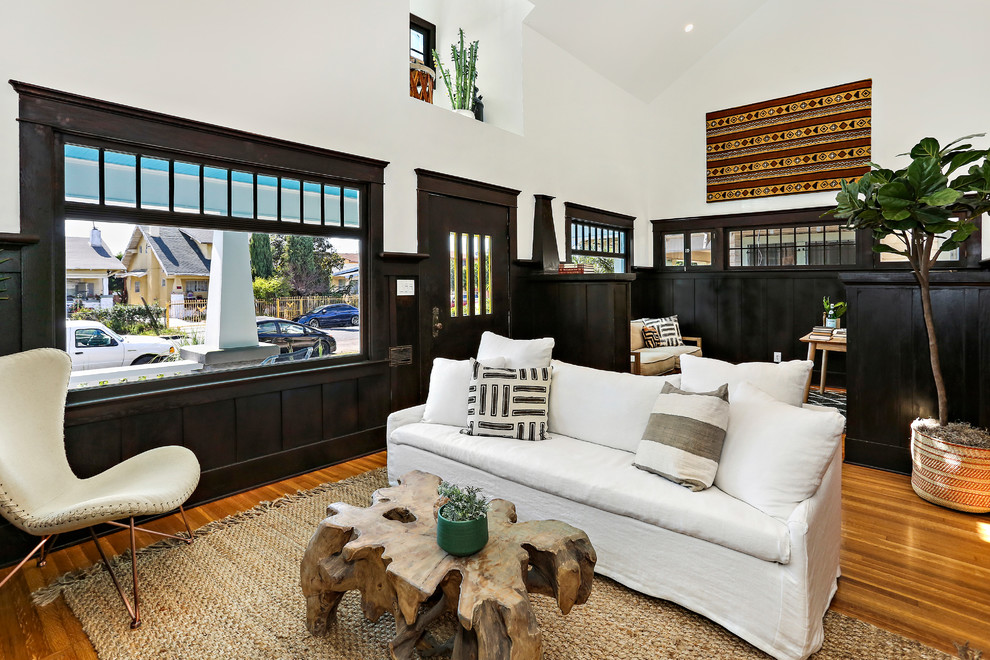 Photo of an eclectic living room in Los Angeles with white walls, medium hardwood floors and brown floor.
