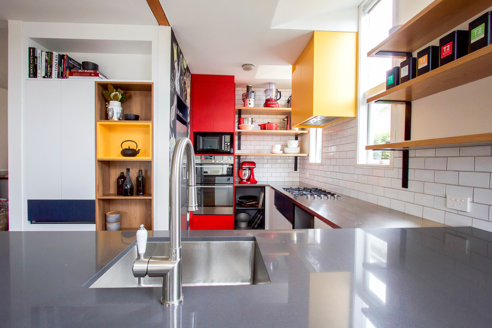 Photo of a small contemporary eat-in kitchen in Auckland with a single-bowl sink, stainless steel benchtops, white splashback, subway tile splashback, stainless steel appliances, medium hardwood floors, no island and grey benchtop.
