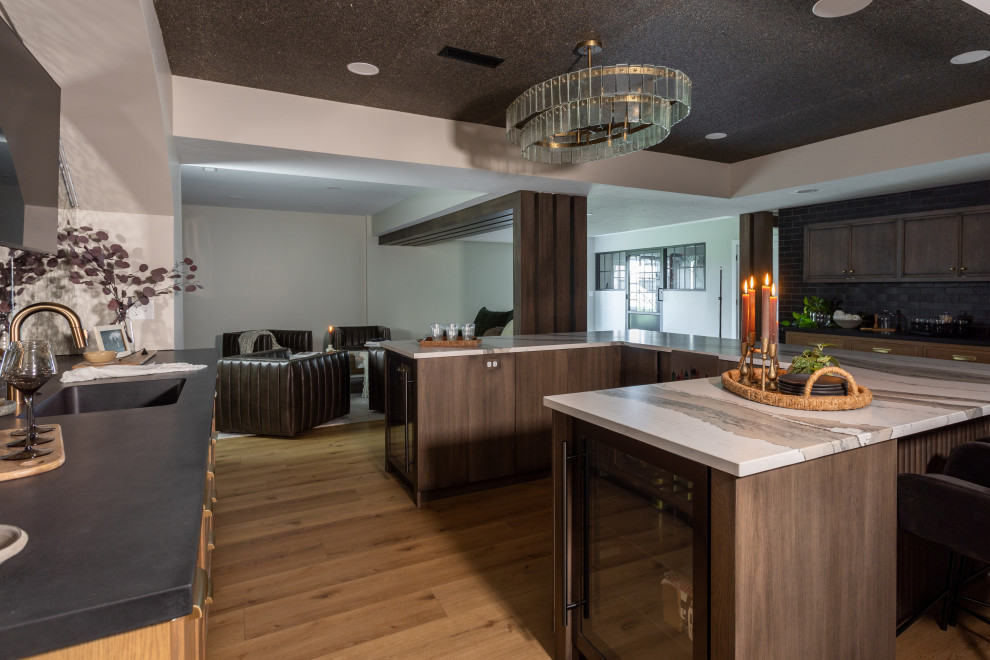 Photo of a transitional u-shaped seated home bar in Cleveland with an undermount sink, shaker cabinets, medium wood cabinets, marble benchtops, vinyl floors, brown floor and white benchtop.