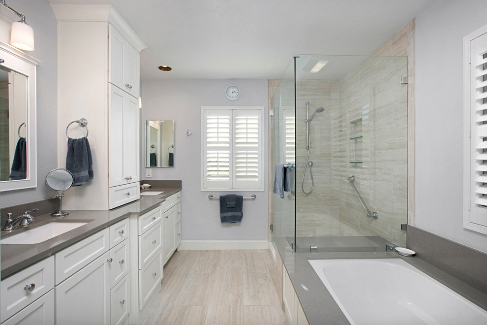 Design ideas for a large modern master bathroom in San Diego with recessed-panel cabinets, white cabinets, a drop-in tub, a corner shower, a two-piece toilet, beige tile, white walls, porcelain floors, a drop-in sink, porcelain tile, engineered quartz benchtops, a hinged shower door, grey benchtops and a built-in vanity.