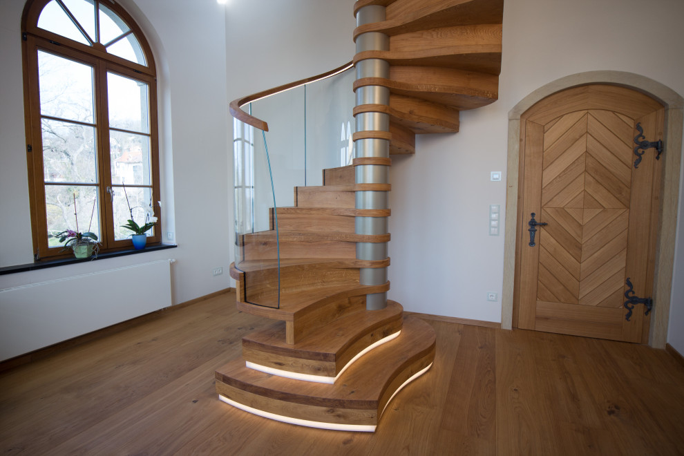 Imagen de escalera de caracol contemporánea grande con escalones de madera, contrahuellas de madera, barandilla de vidrio y papel pintado