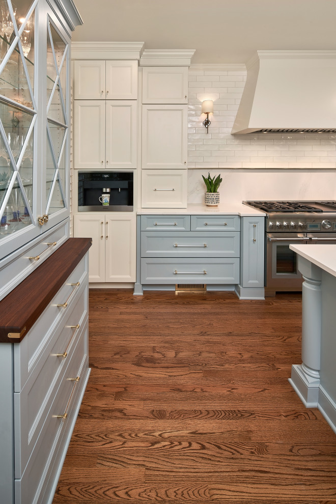 Mid-sized transitional galley medium tone wood floor and brown floor eat-in kitchen photo in Charlotte with a farmhouse sink, recessed-panel cabinets, blue cabinets, quartz countertops, white backsplash, quartz backsplash, stainless steel appliances, an island and white countertops
