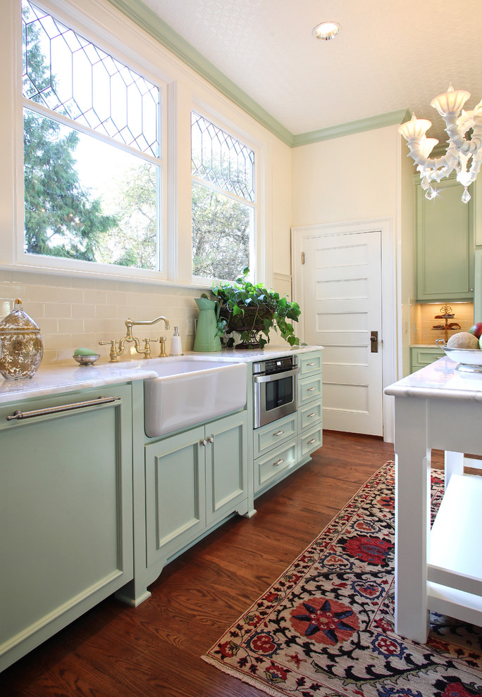 Traditional kitchen in Portland with stainless steel appliances, a farmhouse sink, recessed-panel cabinets, green cabinets, quartz benchtops and white splashback.