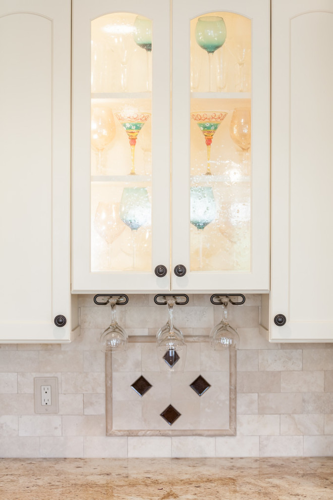 Enclosed kitchen - mid-sized transitional u-shaped light wood floor enclosed kitchen idea in Boston with granite countertops, beige backsplash, stone tile backsplash, stainless steel appliances, a double-bowl sink, recessed-panel cabinets, white cabinets and an island