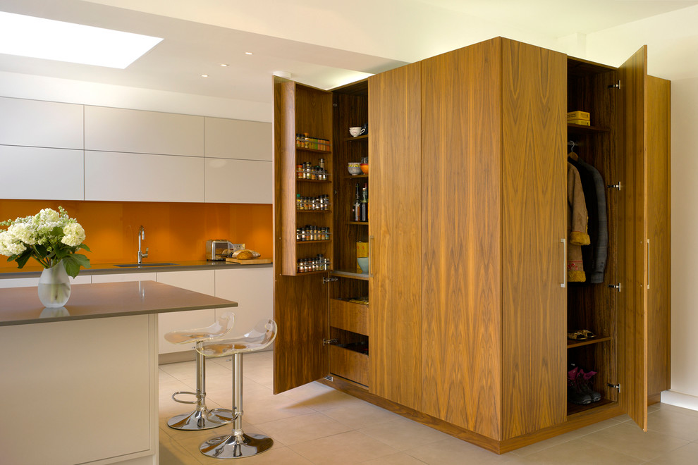 Inspiration for a large contemporary kitchen in London with with island, flat-panel cabinets, medium wood cabinets, solid surface benchtops, orange splashback, glass sheet splashback and an undermount sink.