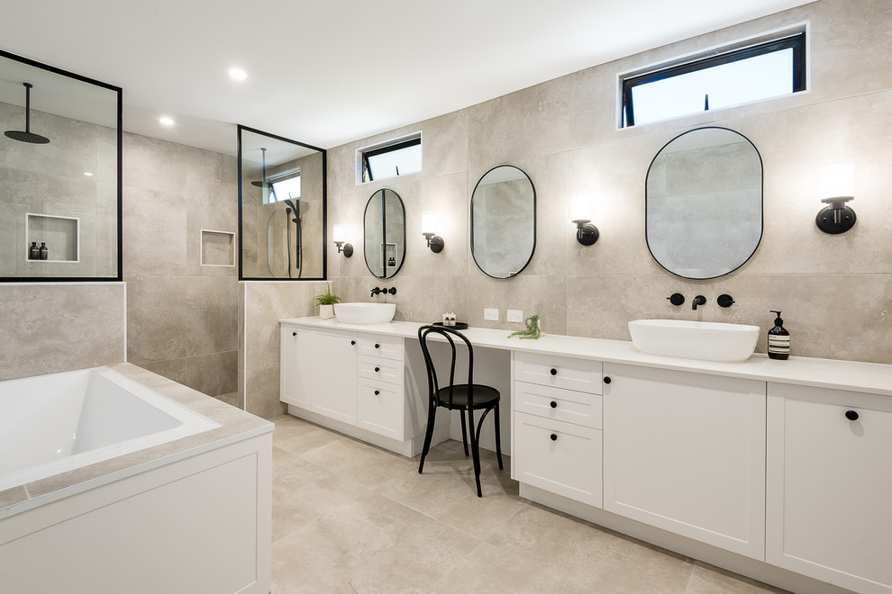 Design ideas for a large contemporary master bathroom in Brisbane with shaker cabinets, white cabinets, a drop-in tub, a double shower, a one-piece toilet, beige tile, porcelain tile, beige walls, porcelain floors, a console sink, solid surface benchtops, beige floor, an open shower and beige benchtops.