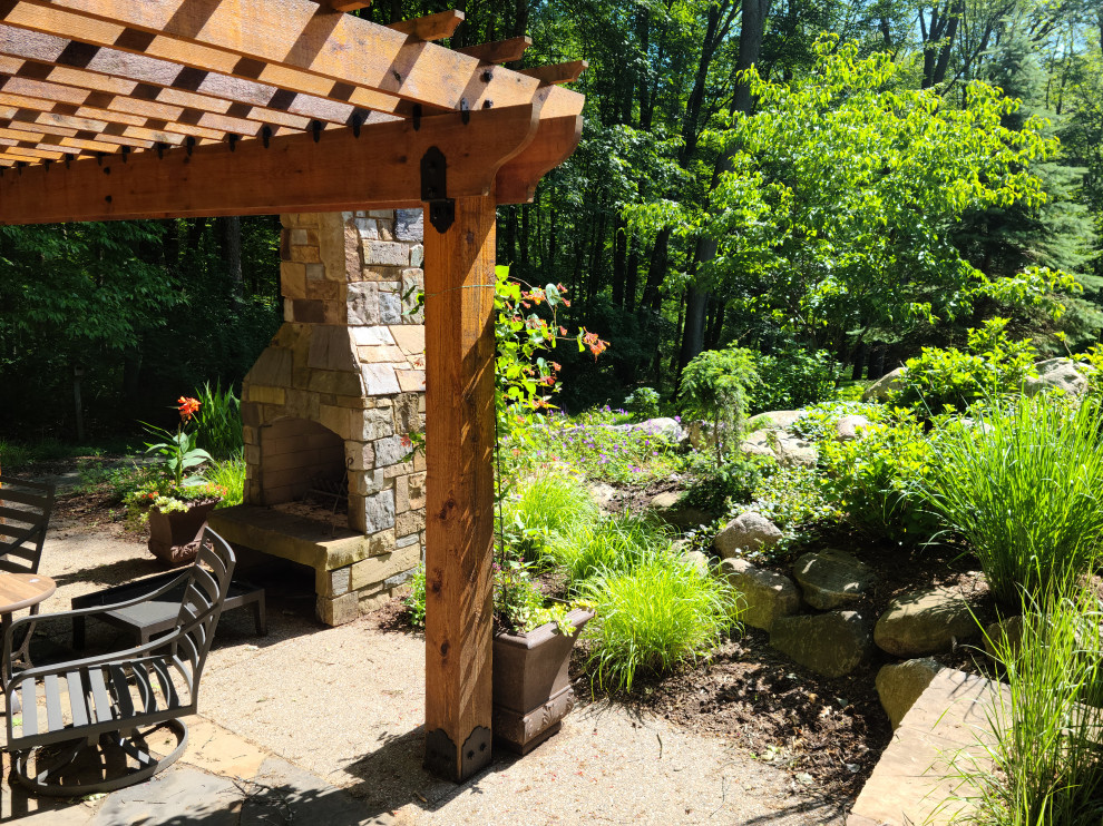 Arts and crafts backyard full sun garden in Grand Rapids with with fireplace and natural stone pavers for summer.