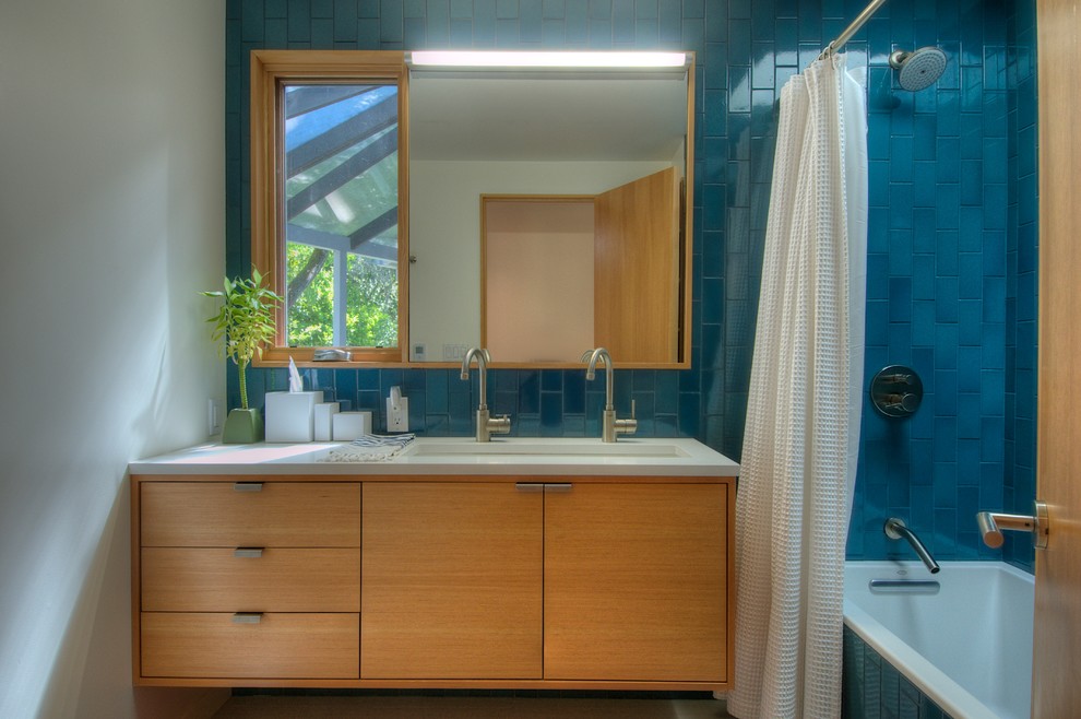 Photo of a midcentury bathroom in San Francisco with flat-panel cabinets, medium wood cabinets, an alcove tub, a shower/bathtub combo, blue tile and subway tile.