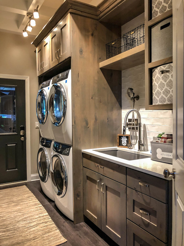 Inspiration for a large modern galley utility room in Chicago with a drop-in sink, distressed cabinets, quartz benchtops, beige walls, dark hardwood floors, a stacked washer and dryer, grey floor and white benchtop.