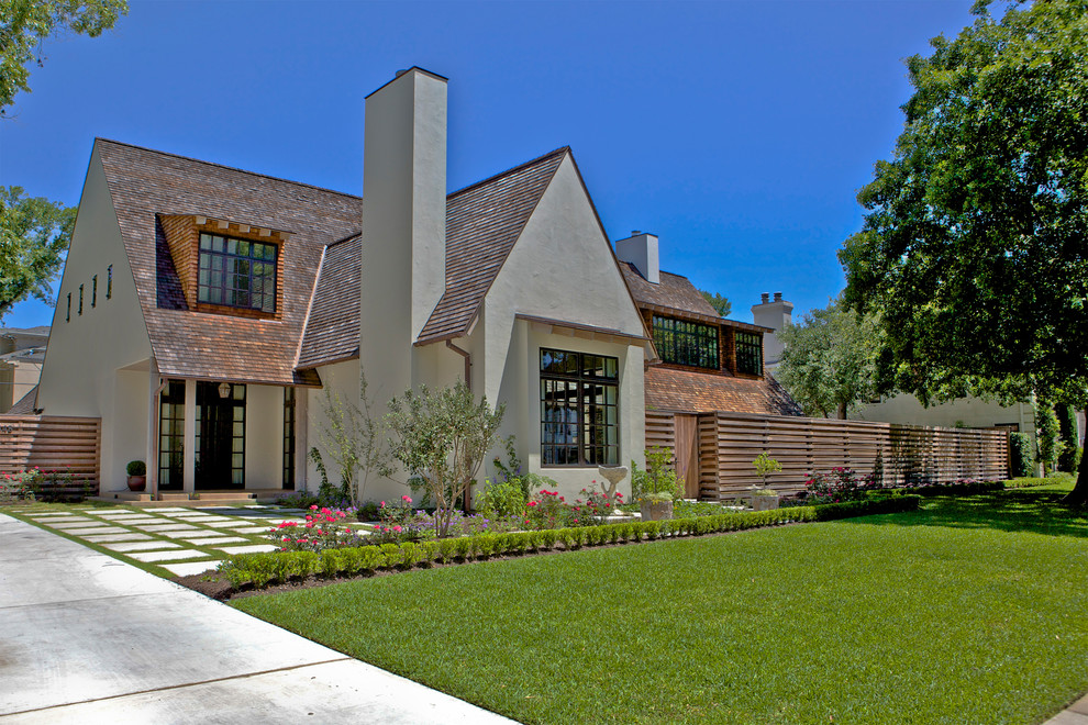 Large arts and crafts two-storey stucco white house exterior with a gable roof and a shingle roof.