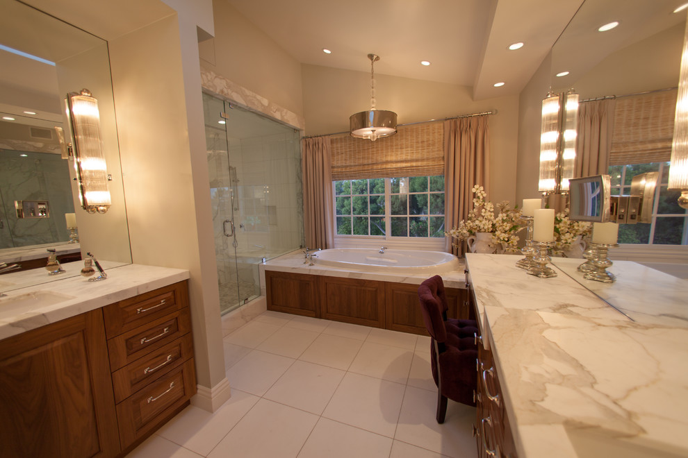 Contemporary bathroom in San Diego with an undermount sink, raised-panel cabinets, medium wood cabinets, marble benchtops, a drop-in tub, an alcove shower, white tile and stone tile.