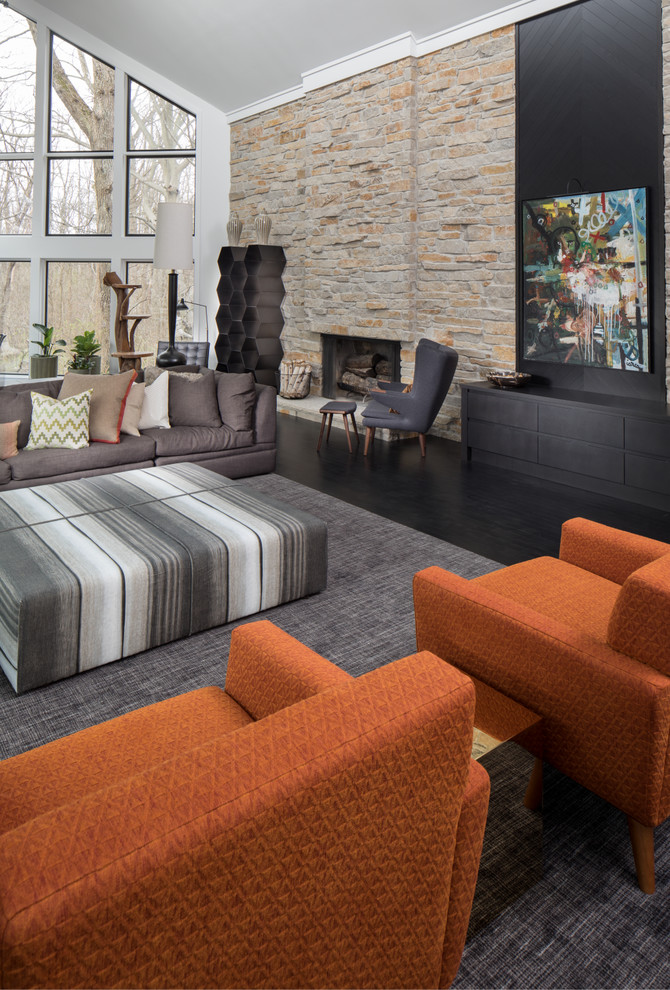 Inspiration for an expansive transitional open concept living room in Indianapolis with grey walls, dark hardwood floors, a standard fireplace, a stone fireplace surround, a wall-mounted tv and black floor.
