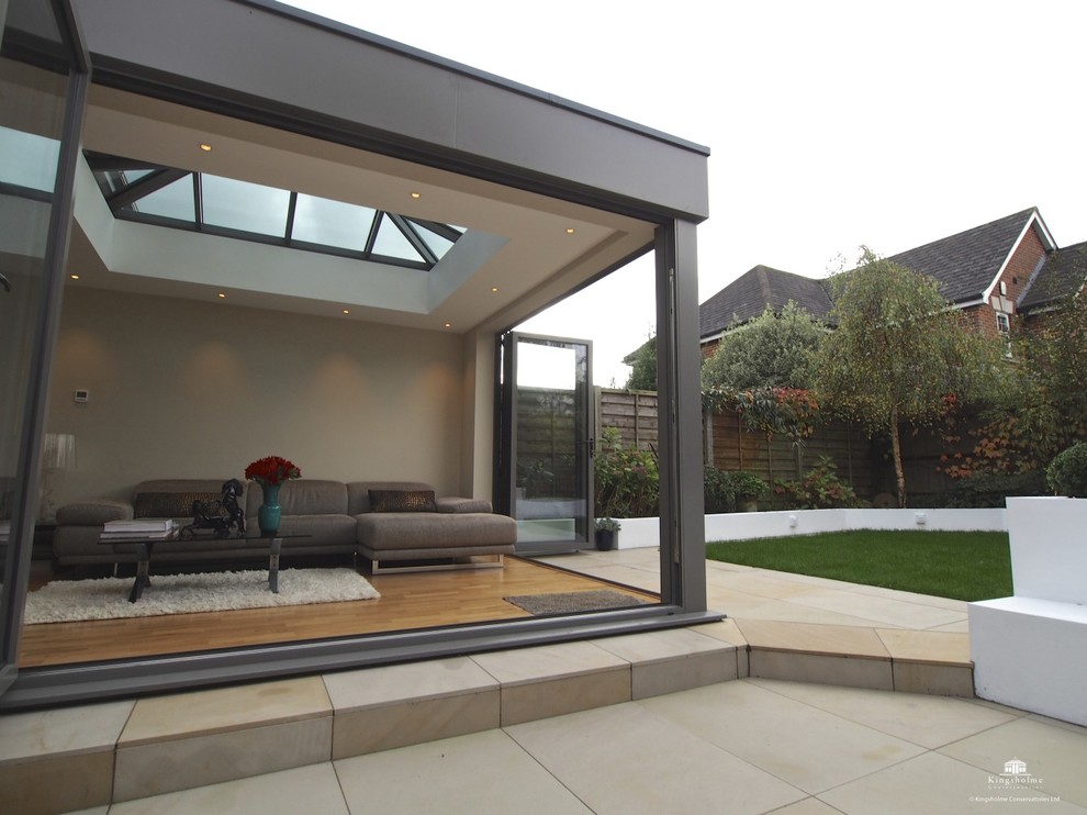 This is an example of a mid-sized contemporary sunroom in London with light hardwood floors and a glass ceiling.