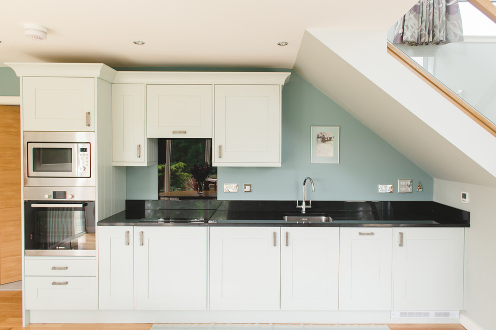 Photo of a transitional kitchen in Glasgow with medium hardwood floors, an undermount sink, shaker cabinets, white cabinets and stainless steel appliances.