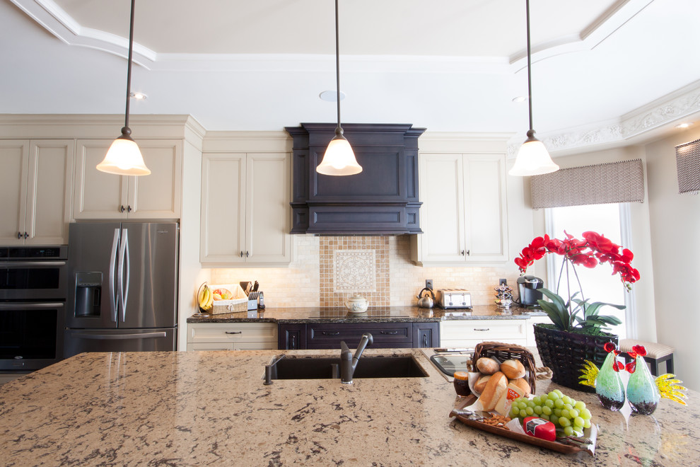 Example of a mid-sized transitional single-wall kitchen design in Toronto with an undermount sink, recessed-panel cabinets, beige cabinets, granite countertops, beige backsplash, ceramic backsplash, stainless steel appliances and an island
