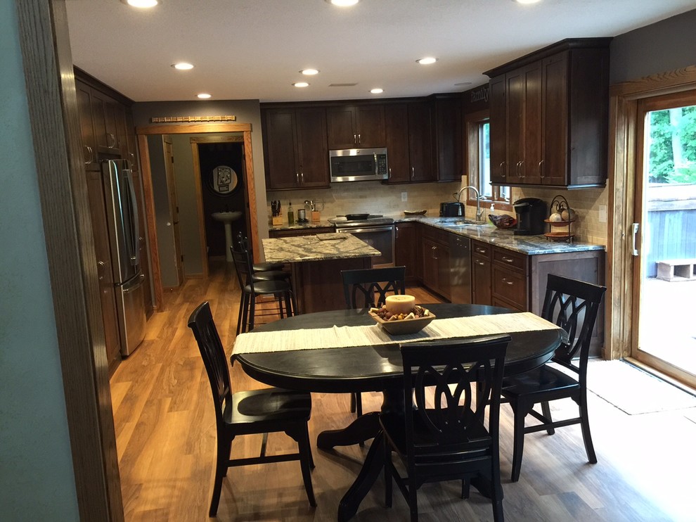 Large medium tone wood floor kitchen photo in Minneapolis with an undermount sink, dark wood cabinets, white backsplash, stainless steel appliances and an island