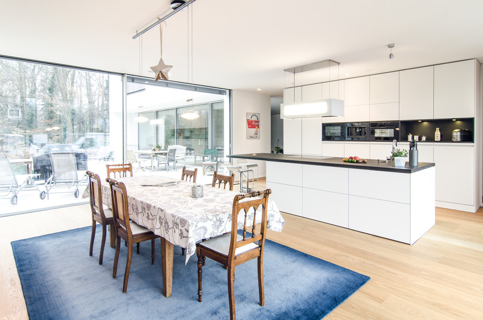 This is an example of a large contemporary open plan dining in Frankfurt with white walls, light hardwood floors, no fireplace and beige floor.