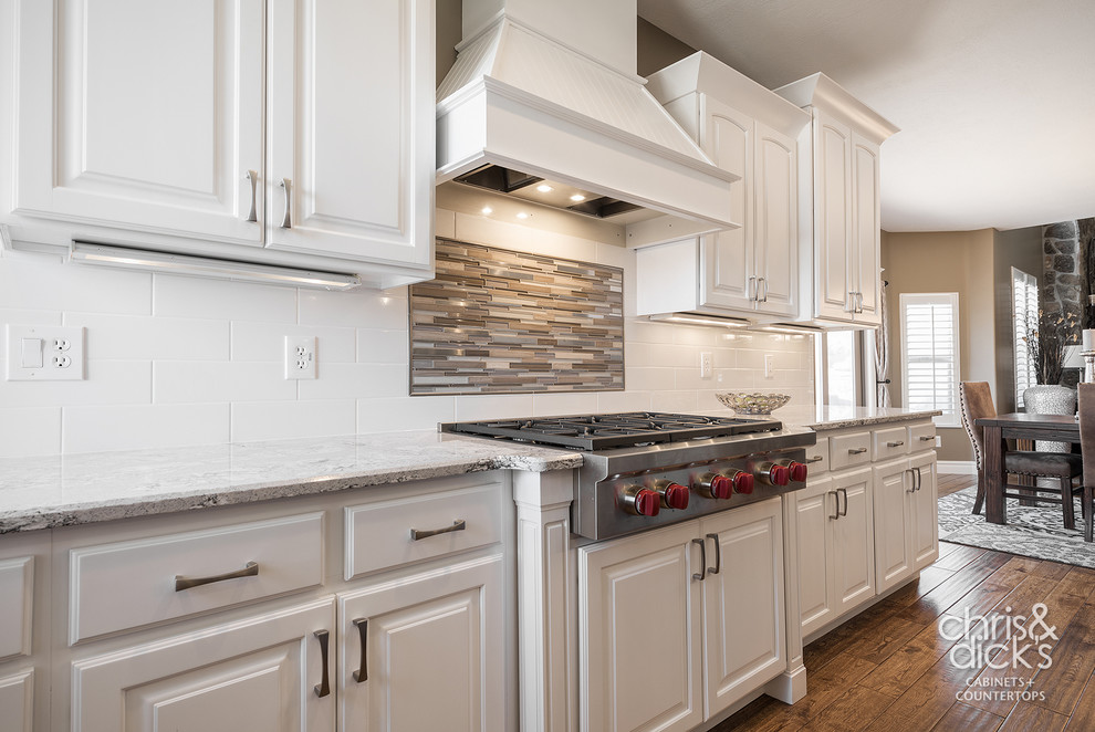 Inspiration for a large traditional l-shaped open plan kitchen in Salt Lake City with an undermount sink, raised-panel cabinets, white cabinets, quartz benchtops, white splashback, ceramic splashback, stainless steel appliances, medium hardwood floors and with island.