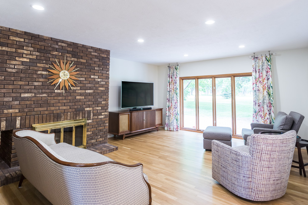 Inspiration for a mid-sized midcentury formal open concept living room in Omaha with white walls, light hardwood floors, a two-sided fireplace, a brick fireplace surround, a freestanding tv and white floor.