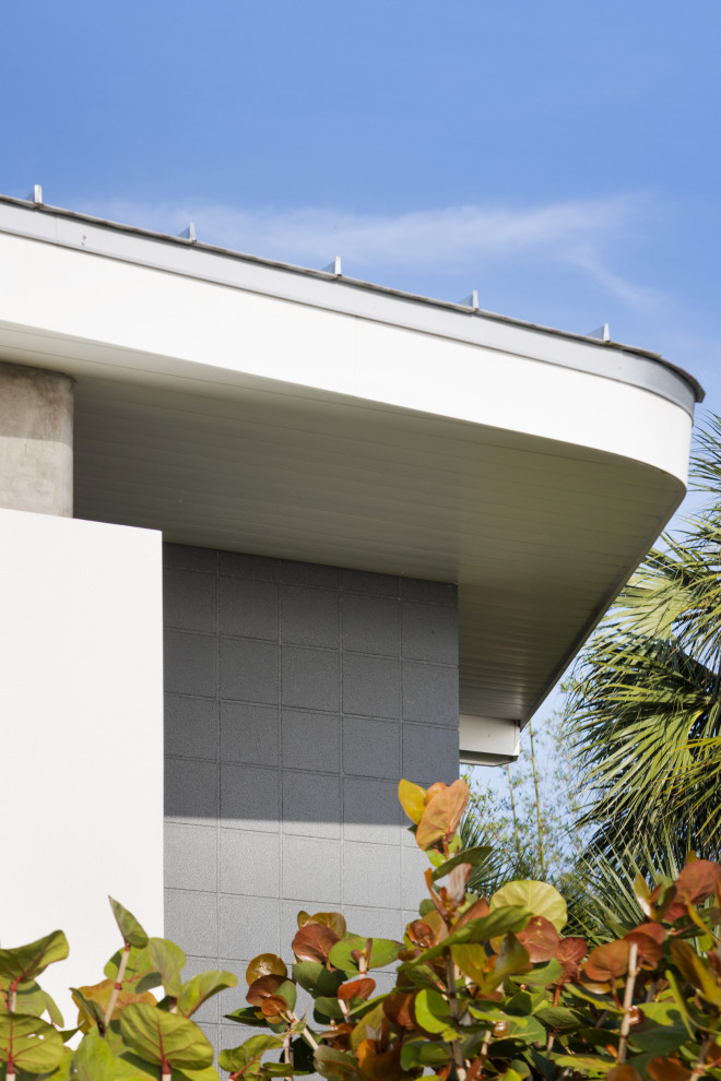 Immagine della micro casa piccola bianca contemporanea a un piano con rivestimento in stucco, copertura in metallo o lamiera e tetto grigio