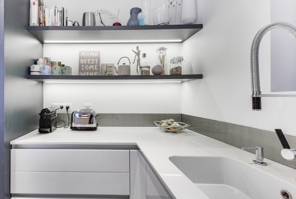 This is an example of a small scandinavian u-shaped eat-in kitchen in Other with an integrated sink, flat-panel cabinets, white cabinets, quartzite benchtops, grey splashback, glass sheet splashback, panelled appliances, ceramic floors, no island, brown floor and white benchtop.