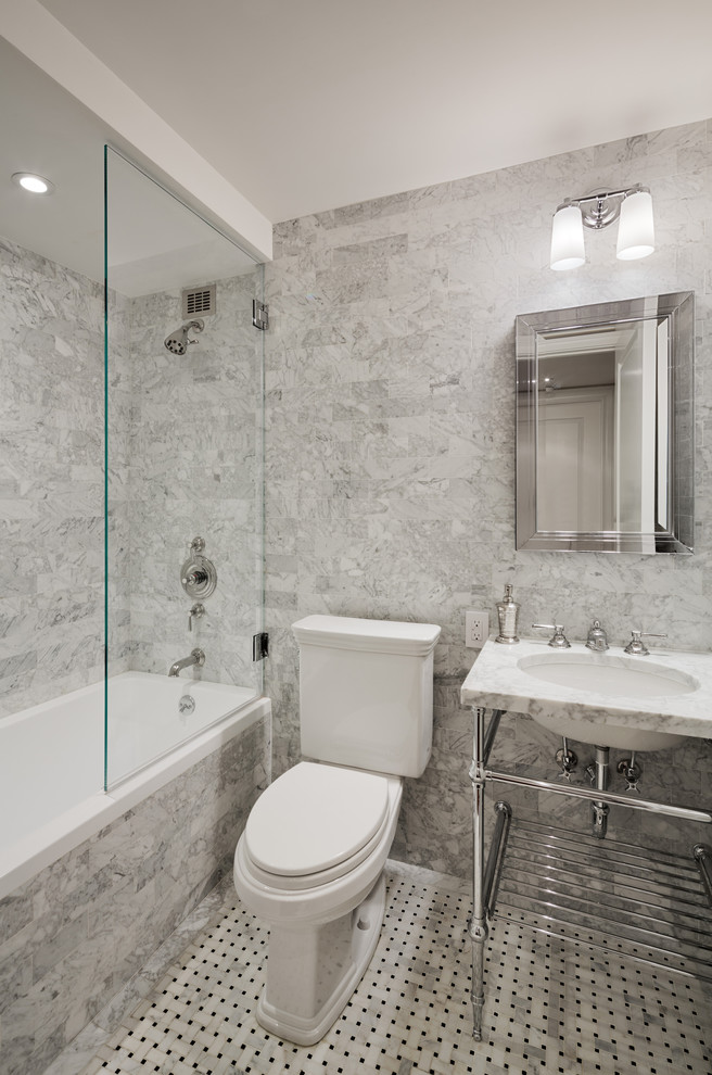 This is an example of a mid-sized transitional bathroom in New York with an alcove tub, a shower/bathtub combo, a two-piece toilet, gray tile, open cabinets, marble, grey walls, marble floors, a console sink and marble benchtops.