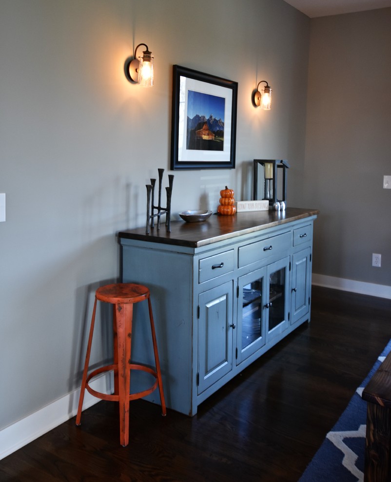 Photo of a mid-sized arts and crafts kitchen/dining combo in Kansas City with grey walls, dark hardwood floors, a standard fireplace and a stone fireplace surround.