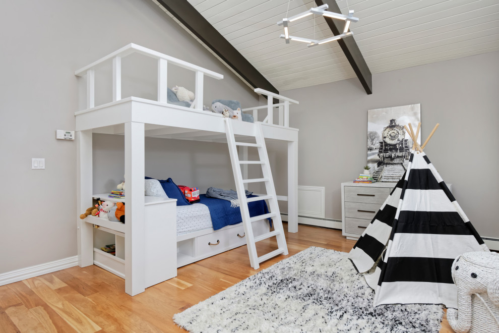 Modelo de dormitorio infantil actual de tamaño medio con paredes beige y suelo de madera en tonos medios