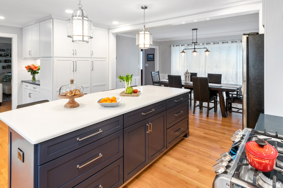 Mid-sized transitional l-shaped medium tone wood floor and brown floor eat-in kitchen photo in Raleigh with an undermount sink, shaker cabinets, white cabinets, quartz countertops, gray backsplash, porcelain backsplash, stainless steel appliances, an island and gray countertops