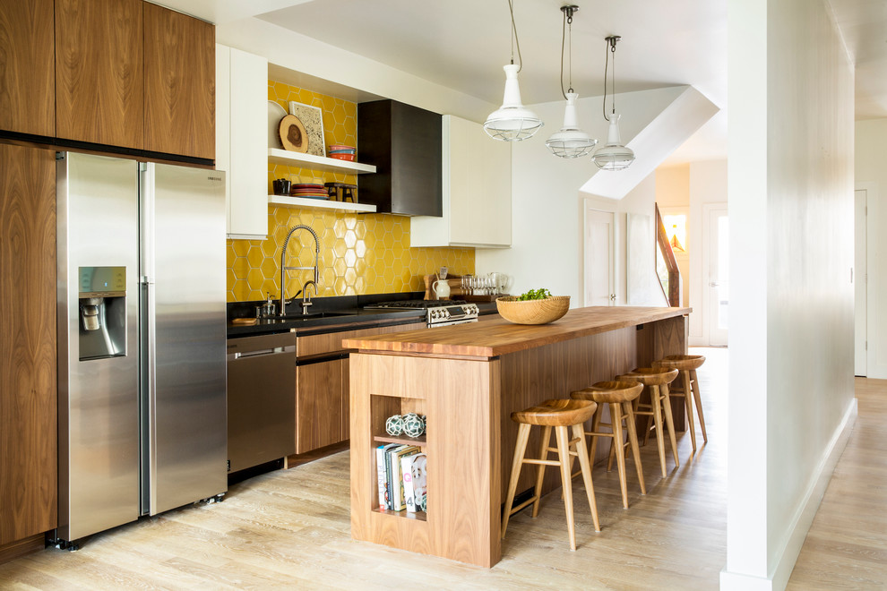 This is an example of a mid-sized contemporary single-wall kitchen in San Francisco with an undermount sink, flat-panel cabinets, wood benchtops, yellow splashback, ceramic splashback, stainless steel appliances, light hardwood floors, with island and medium wood cabinets.