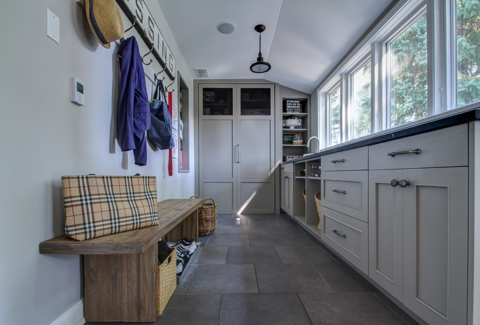 This is an example of a traditional laundry room in Chicago with grey cabinets and grey floor.